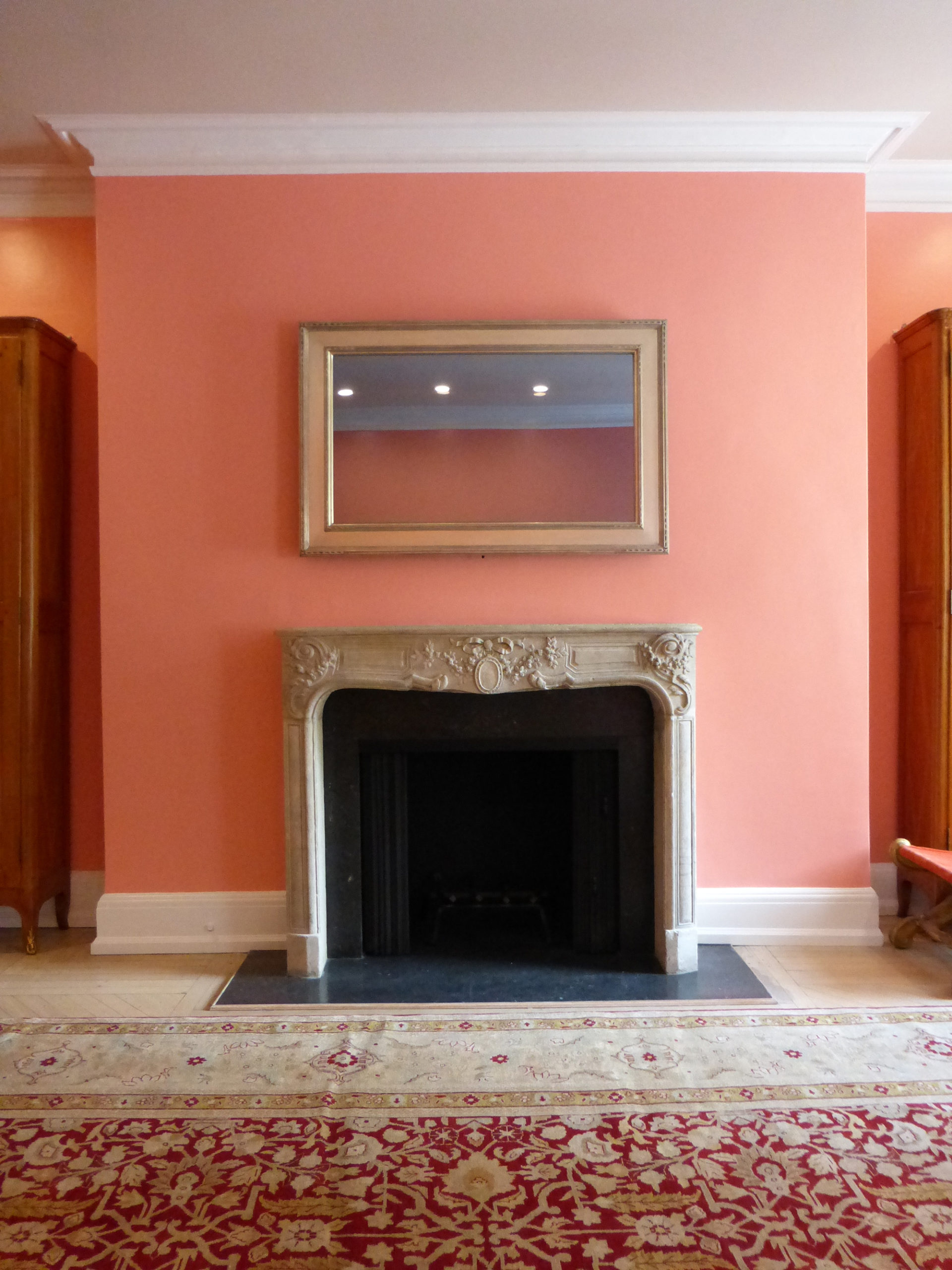 gold reflectel mirror tv over stone mantle on peach wall