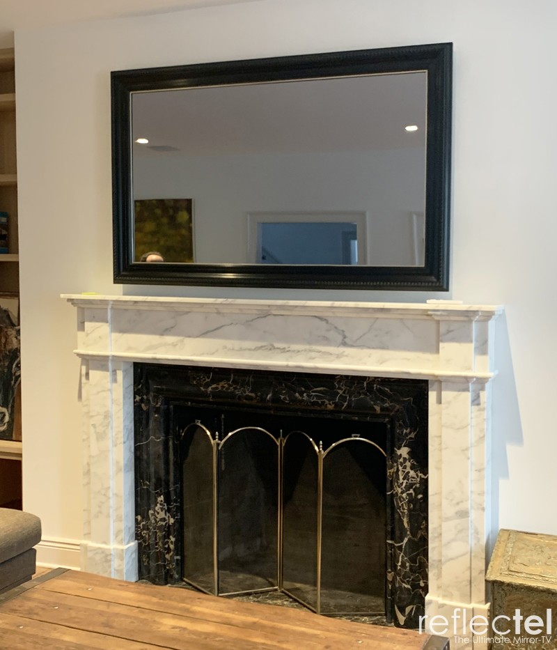 Landscape Mirror Television With Specialty Wood Frame Over Marble Fireplace