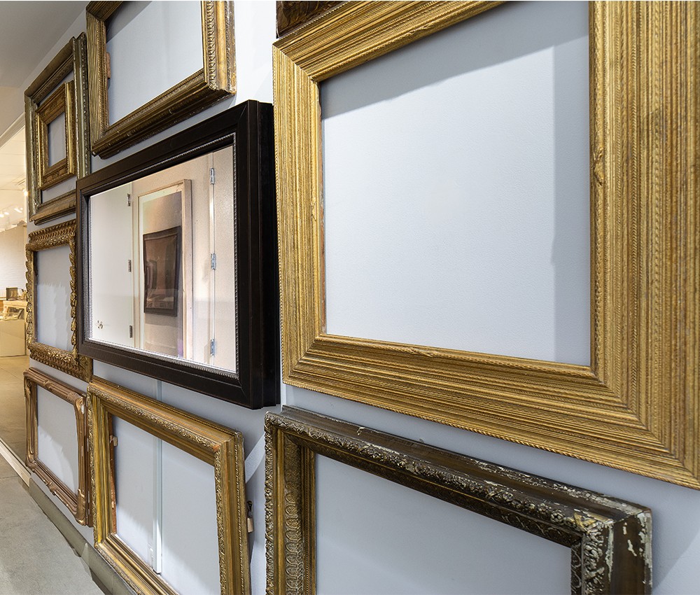 Antique Gilded Frames On White Wall In Reflectel Frame Shop Hallway With Turned Off Mirror Television