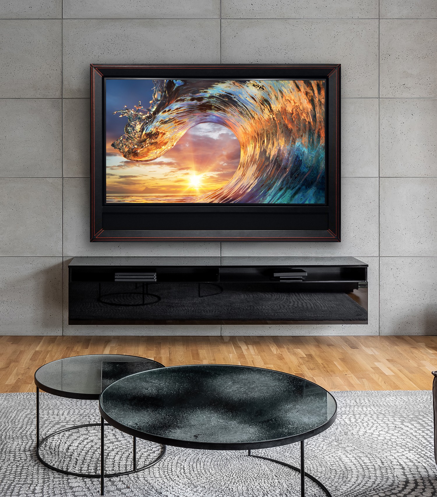 black leather framed tv with red stitching, image of wave, over a black console in room with hardwood floors, grey rug and rounded glass coffee tables
