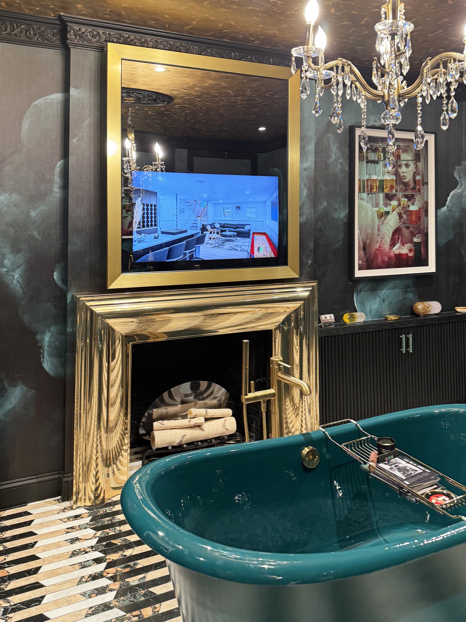 Gold Frame with TV on over a Gold Fireplace Mantel with a Green Tub in Center of the Room