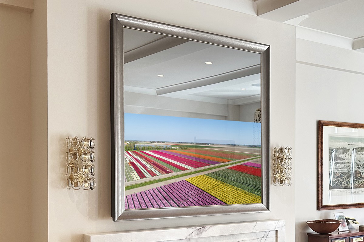 Silver framed tv on a mirror in a square shape over marble fireplace