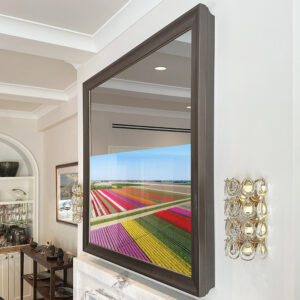 Square Mirror TV with a silver frame over marble fireplace turned on