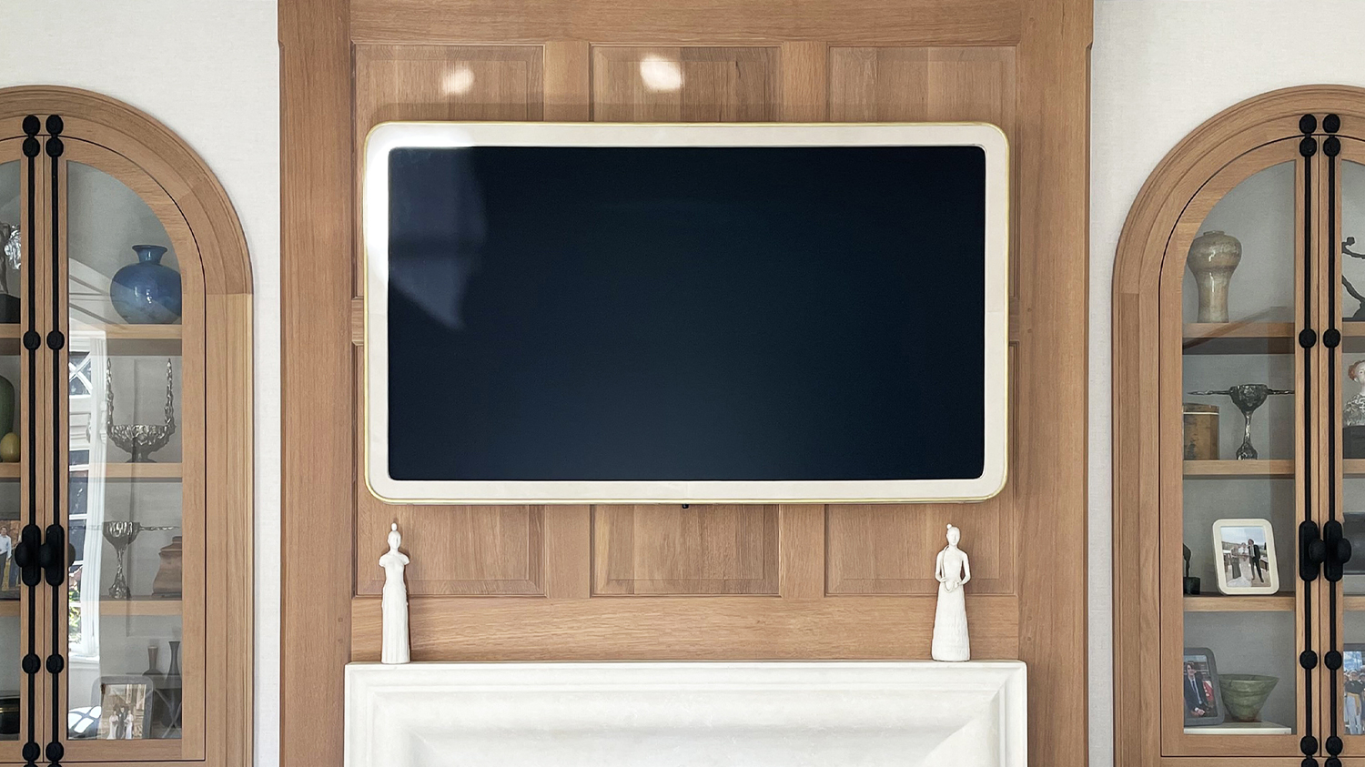 Framed TV With A White Leather Frame Over White Mantel Fireplace