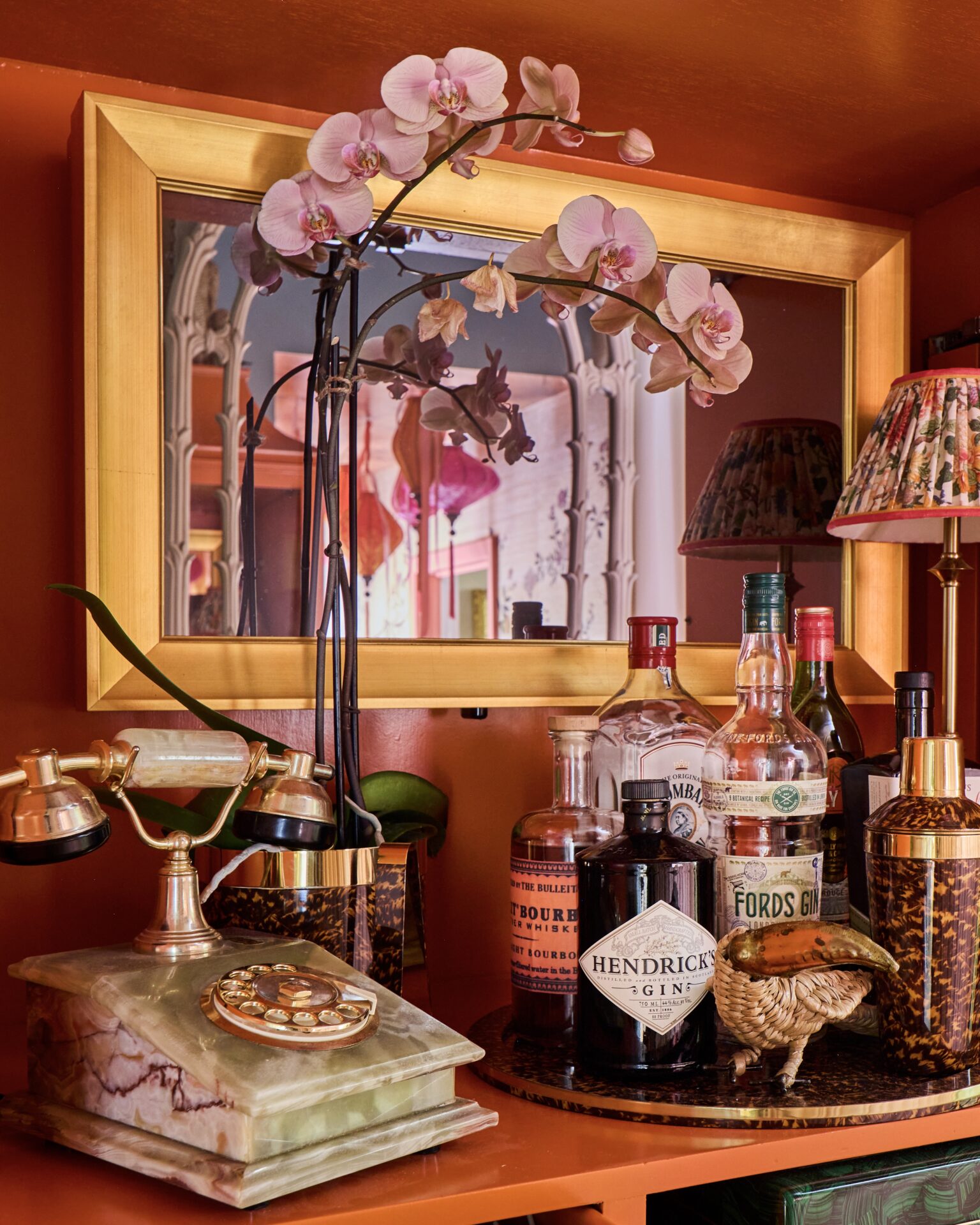 hidden tv mirror in cabinet with gold tv frame mirror off with orchids, bar, marble telephone around it in tartan an toile's kips bay showhouse palm beach room