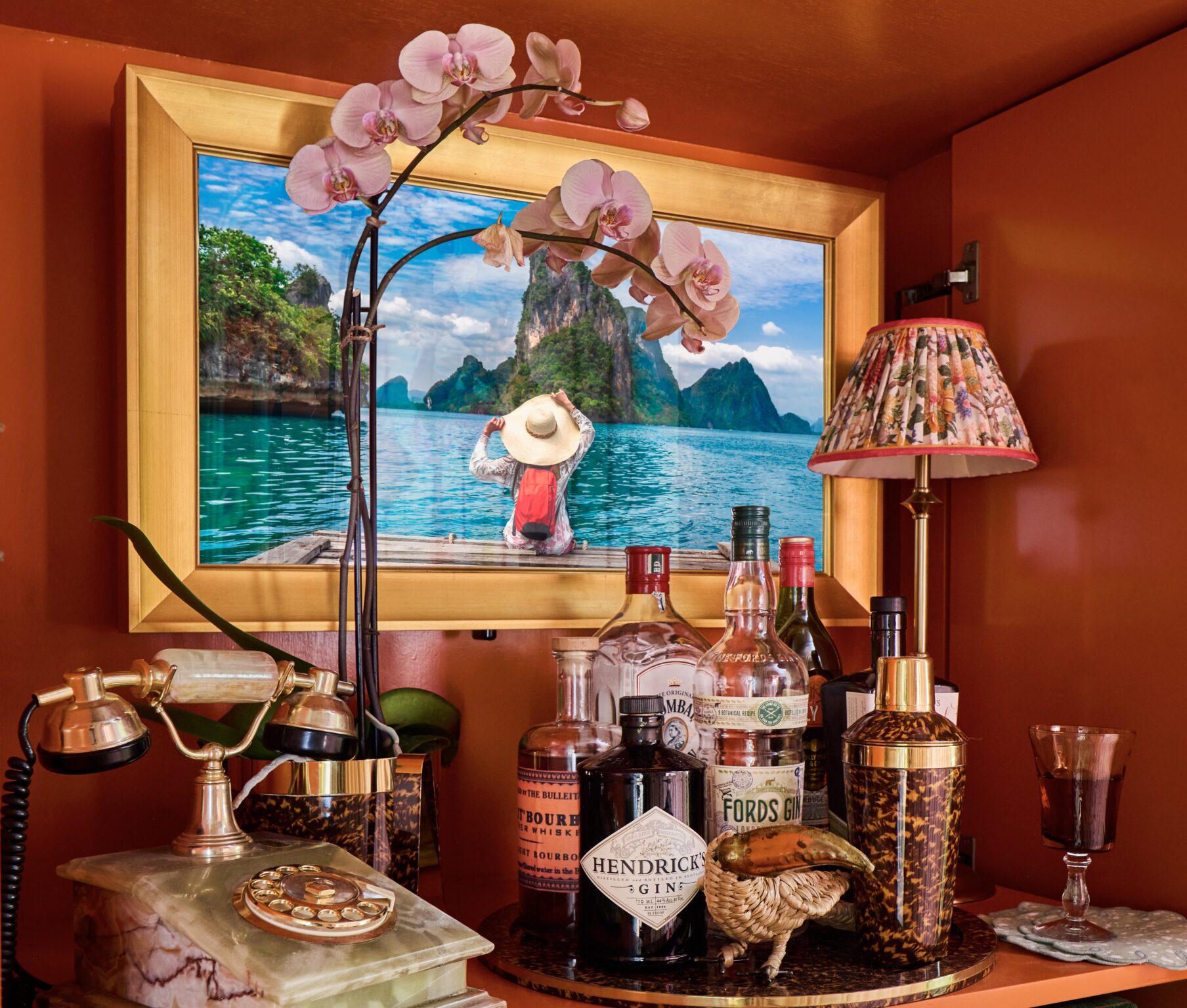 gold framed tv in mirror with tv on and the framed tv is inside cabinet bar with marble phone, flowers, backlit bar cabinet in the kips bay decorator show house palm beach designer tartan and toile