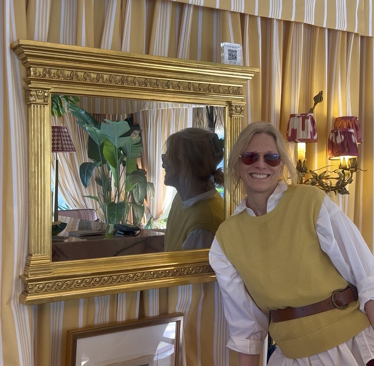 reflectel mirror tv founder elizabeth goldfeder in the tiki tent by river brook interiors next to gold carved framed tv in mirror at the kips bay show house palm beach