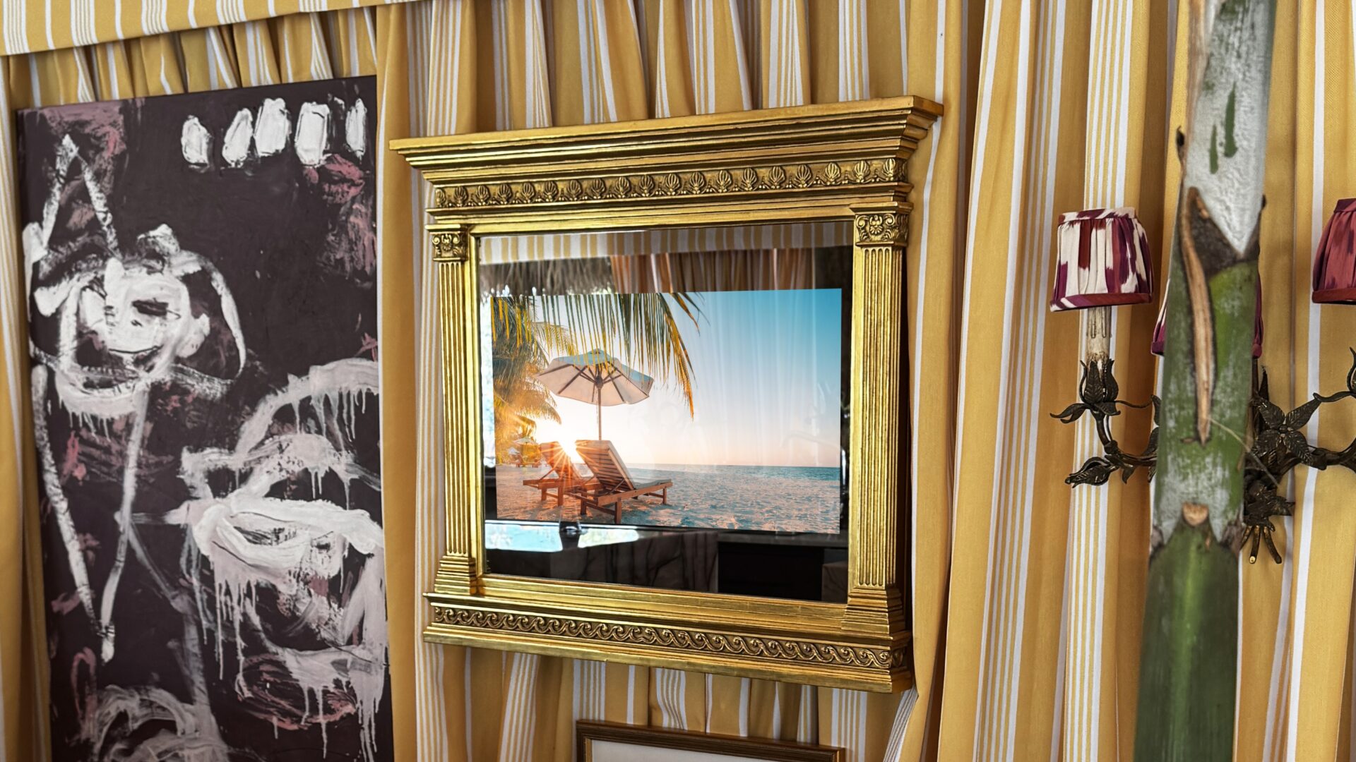 gilded tabernacle framed tv in mirror, gold tv mirror frame in cabana tiki tent surrounded by artwork and plants at kips bay showhouse palm beach