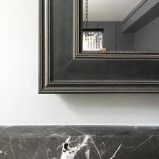 Signature Shaped - SS3-B minimalistic black frame corner of high end television mirror turned off over marble mantel