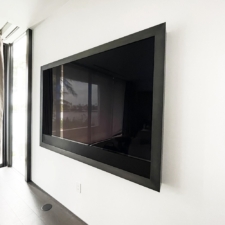 77" Landscape - Specialty Metal Framed TV/No Mirror with soundbar Framed TV with a dark steel metal frame on white wall