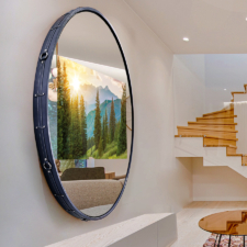 55" Circle - Leather (Cortina - Atlantis) Navy leather frame with strap details on circle mirror television hanging near staircase with image.