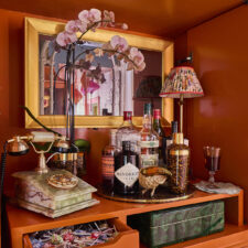 27" Landscape - Signature Shaped - Kips Bay Palm Beach - Tartan & Toile - Photo credit: Laurey Glenn Mirror TV with a gold frame installed in an orange armoire at Kips Bay Palm Beach