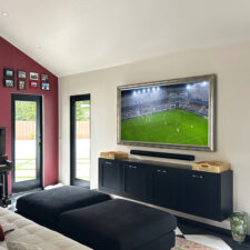75" Landscape - Signature Shaped (SS16-S-O) Mirror tv turned on with football game in living room above media cabinet.
