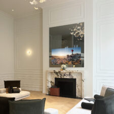 75" Portrait Plus - Custom Millwork Frame Mirror tv with white thin wood frame turned off over fireplce in living room.