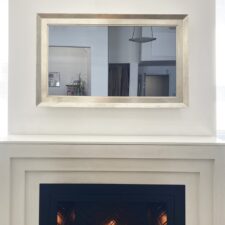 49" Gilded Shaped - Landscape 49" edge to edge luxury tv mirror with white gold frame over lit modern fireplace Reflectel in HearthCabinet NYC