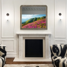 50" TV in Arch Shaped Frame for Chiara de Rege TV behind a silver-framed arched mirror above a white fireplace in an elegantly designed room.