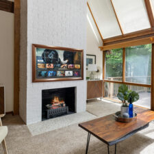65" Landscape - Mahogany with Gilded Liner Wooden framed mirror TV in living room with large windows turned on.
