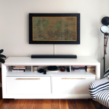 43" Landscape - Signature Flats Black and gold framed Reflectel mirror tv turned on over white media cabinet in living room.
