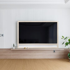 83" Framed TV w/ soundbar - Leather Light colored framed television turned off with shelf underneath in living room.
